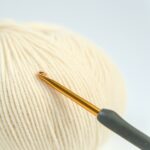 Tulip Mind ergonomický háčik opretý o klbko priadze, kvalitný kovový háčik s protišmykovou rukoväťou.