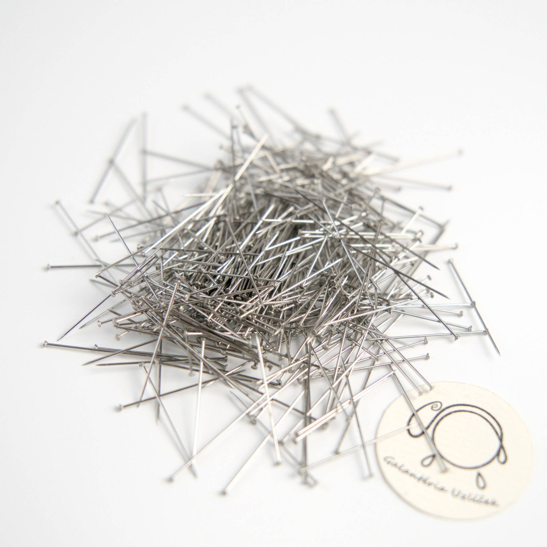 nerezove-spendliky-nerezovy-spendlik-26-mm-0,5-mm-celokovovy-nehrdzavejuci-01 Vysypané nerezové špendlíky na stole, 440 kusov