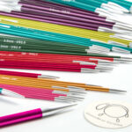 Kovové ponožkové ihlice KnitPro Zing rozsypané na stole